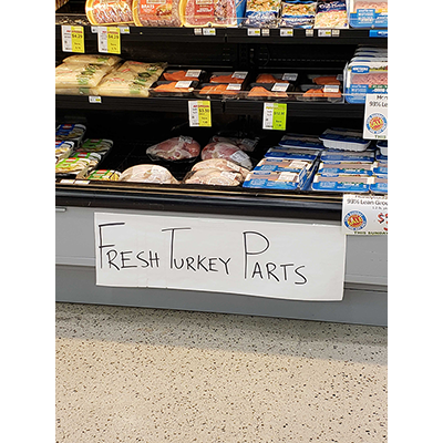 Hand drawn sign at grocery store advertising fresh turkey parts.